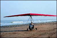 The ultralight taxies down the beach and takes off with Mark Manuel hanging onto Dr. Mazda for dear life!