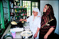 Abida supervising one of her ethathas cooking in the modern kitchen.