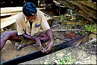A carpenter sharpens the teeth of the large saw that is used to cut wood for the dhow.