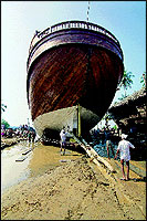 A dhow being launched into the sea through a small inlet at Beypore by experts known as khalasis. The job is done physically, using steel ropes, wooden rollers and rounded logs, wooden pulleys and winches.