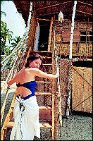 Florence entering her one storey straw thatched hut where she has a very good relationship with her bed, when reading, sleeping, or making love!