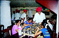 A Golden Star waiter, in the trademark Rajasthani dhoti-kurta and red pagdi, serving a table.